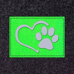 May include: A rectangular patch with a lime green background and a grey heart and paw print design. The heart shape partially surrounds the paw print. The patch has a black stitched border and is set against a dark grey textured background.