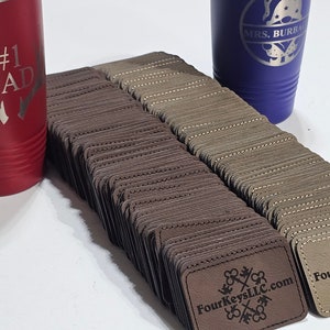 May include: A stack of brown leather labels with the text "FourKeysLLC.com" and a logo of four keys intertwined. The labels are stacked on a white surface.