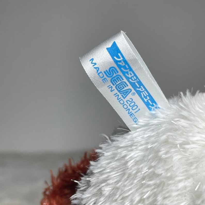 May include: White and brown plush toy with a blue and white label that reads "SEGA 2001" and "Made in Indonesia". The label also has Japanese text that reads "ソニック・ザ・ヘッジホッグ".