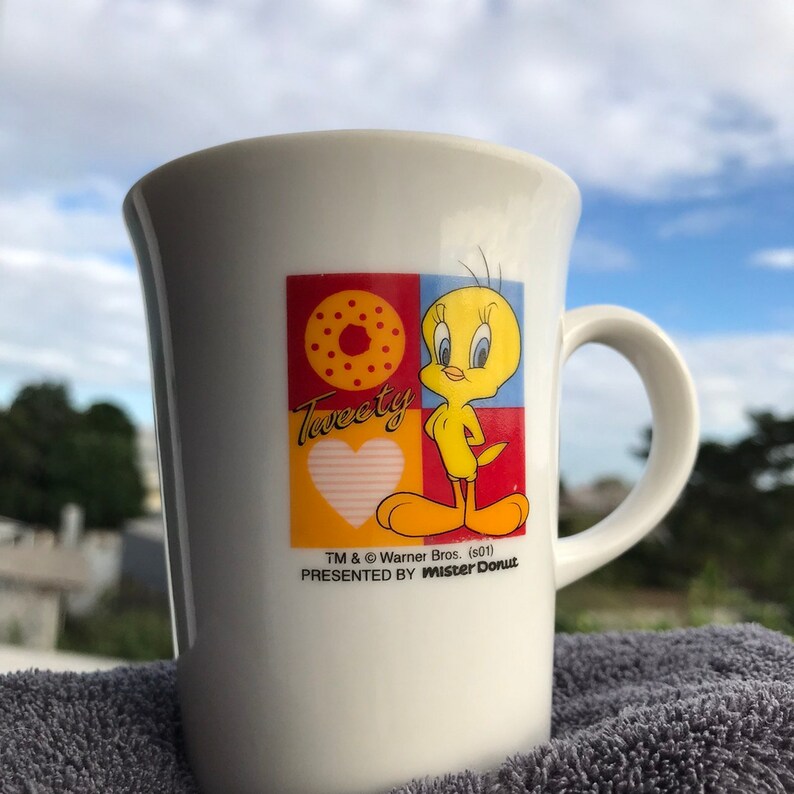 May include: White ceramic mug with a colorful cartoon image of Tweety Bird. The mug has the text "Tweety" and "Presented by Mister Donut" on it.