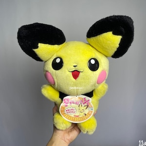 May include: Yellow and black plush Pikachu toy with a red tongue sticking out. The toy has a tag that says "Pichu!" and "Pocket Monsters" in Japanese. The tag also has a picture of Pikachu.