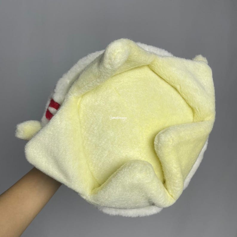 May include: A soft, yellow plush pet bed with a white trim. The bed is shaped like a crown and has a soft, plush lining.