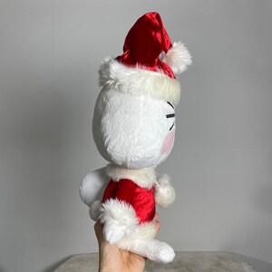 May include: White plush toy wearing a red velvet Santa hat with white fur trim and a red velvet Santa suit with white fur trim.