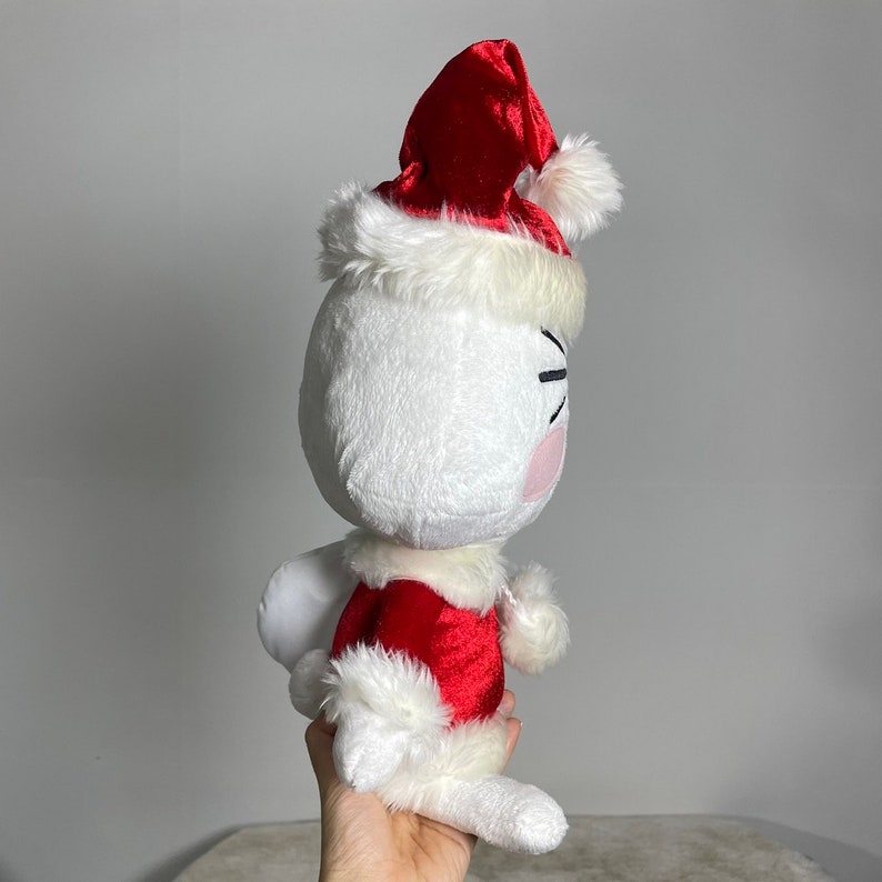 May include: White plush toy wearing a red velvet Santa hat with white fur trim and a red velvet Santa suit with white fur trim.