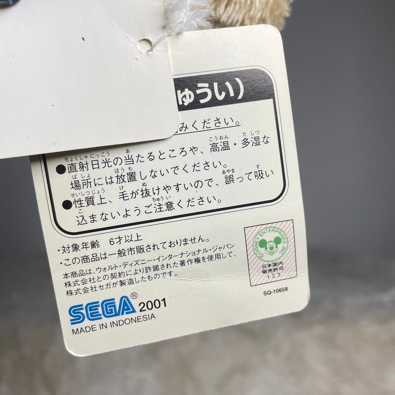 May include: A white plush toy with a tag that reads "ゆうい) みください." The tag also includes instructions for care, such as avoiding direct sunlight and high temperatures, and a warning about the toy's tendency to shed. The tag also states that the toy is made in Indonesia and is for ages 6 and up.