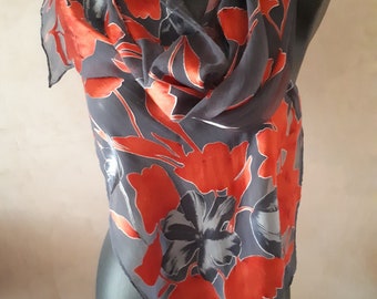 Puede incluir: Una bufanda de seda gris con un patrón floral en tonos naranja y blanco.