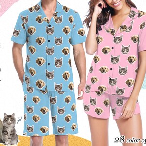 May include: A blue and pink pajama set with a custom face print of a dog and cat. The pajama set features a short-sleeved button-up shirt and matching shorts. The text "Custom Face Pajama" is written vertically on the left side of the image.