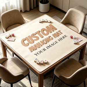 May include: A square beige mahjong mat placed on a wooden table, featuring the text CUSTOM MAHJONG MAT YOUR IMAGE HERE in large brown letters. The mat is surrounded by four beige chairs and includes scattered mahjong tiles, dice, and playing cards.