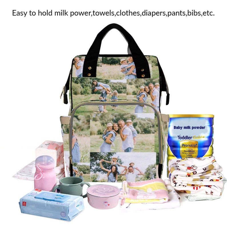 May include: A large, multi-compartment diaper bag with a photo collage of a family on the front. The bag is filled with baby essentials, including a bottle of baby milk powder, a bottle of water, a pack of wipes, a bib, and a small container of food. The bag is sitting on a white surface.