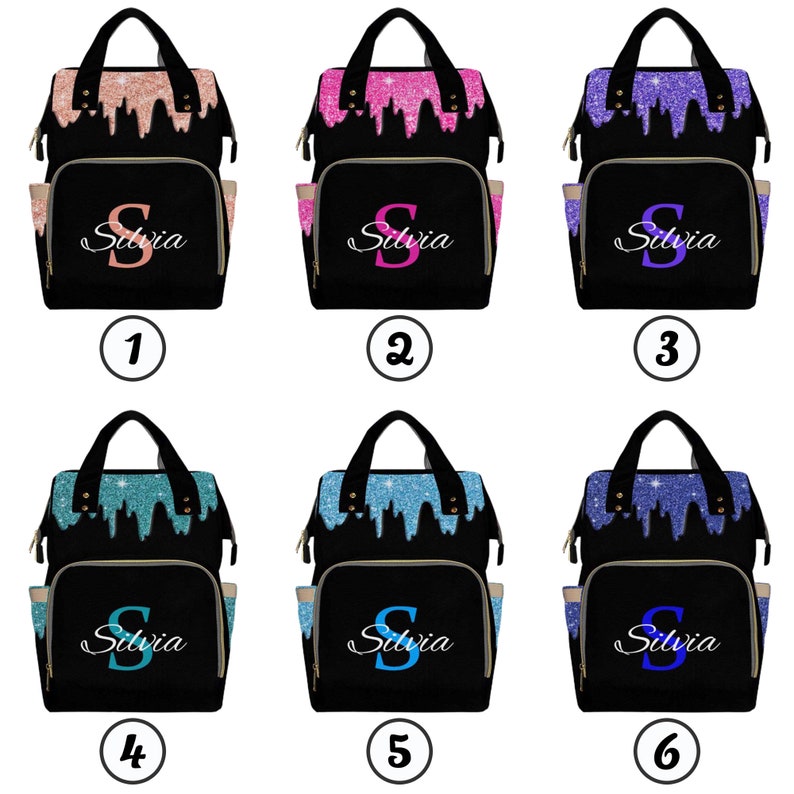 May include: Six black diaper bags with different glitter colors on the front. Each bag has a gold zipper and a gold pocket on the side. The bags are labeled with numbers 1 through 6. The name "Silvia" is written on each bag with a large letter "S" in a different color.