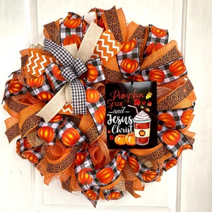 Pu&ograve; includere: Una ghirlanda autunnale con nastro a quadri arancio, nero e bianco, rete arancione e un cartello che recita "Pumpkin Spice and Jesus Christ".