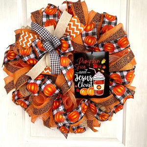 Pu&ograve; includere: Una ghirlanda autunnale con nastro a quadri arancio, nero e bianco, nastro a spirale arancio e marrone e un cartello con la scritta "Pumpkin Spice and Jesus Christ".