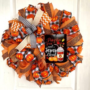 Pu&ograve; includere: Una ghirlanda autunnale con nastro a quadri arancio e nero, nastro arancio con motivo a spirale e un cartello che recita "Pumpkin Spice and Jesus Christ".