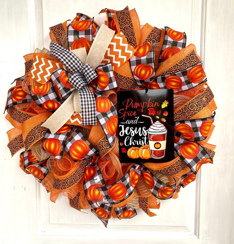 Pu&ograve; includere: Una ghirlanda autunnale con nastro a quadri arancio e nero, nastro arancio a spirale e un cartello che recita "Pumpkin Spice and Jesus Christ".