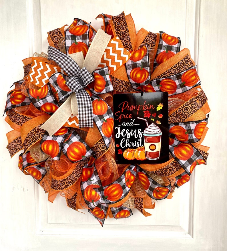 Pu&ograve; includere: Una ghirlanda autunnale con nastro a quadri arancio, nero e bianco, nastro arancio a spirale e un cartello che recita "Pumpkin Spice and Jesus Christ".