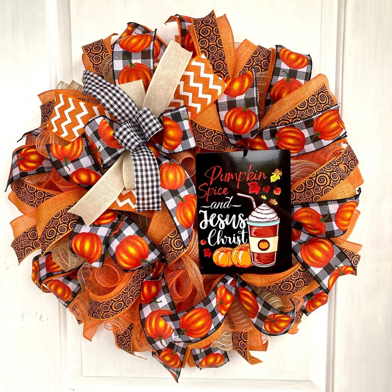 Pu&ograve; includere: Una ghirlanda autunnale con nastro a quadri arancio e nero, nastro a spirale arancio e marrone e un cartello che recita "Pumpkin Spice and Jesus Christ".