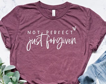 May include: A maroon t-shirt with the text "NOT PERFECT just forgiven" in white lettering with a small heart symbol.