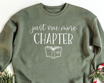 May include: A green sweatshirt with the text "just one more CHAPTER" and a drawing of an open book with a heart on the page.