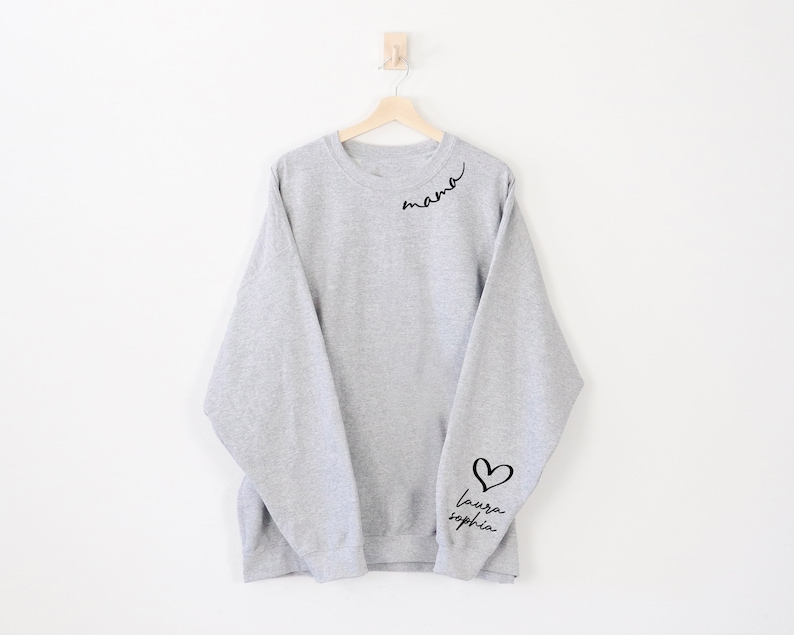 May include: Grey sweatshirt with the word "mama" written in cursive on the left shoulder and a heart with the words "laura sophia" on the right sleeve.