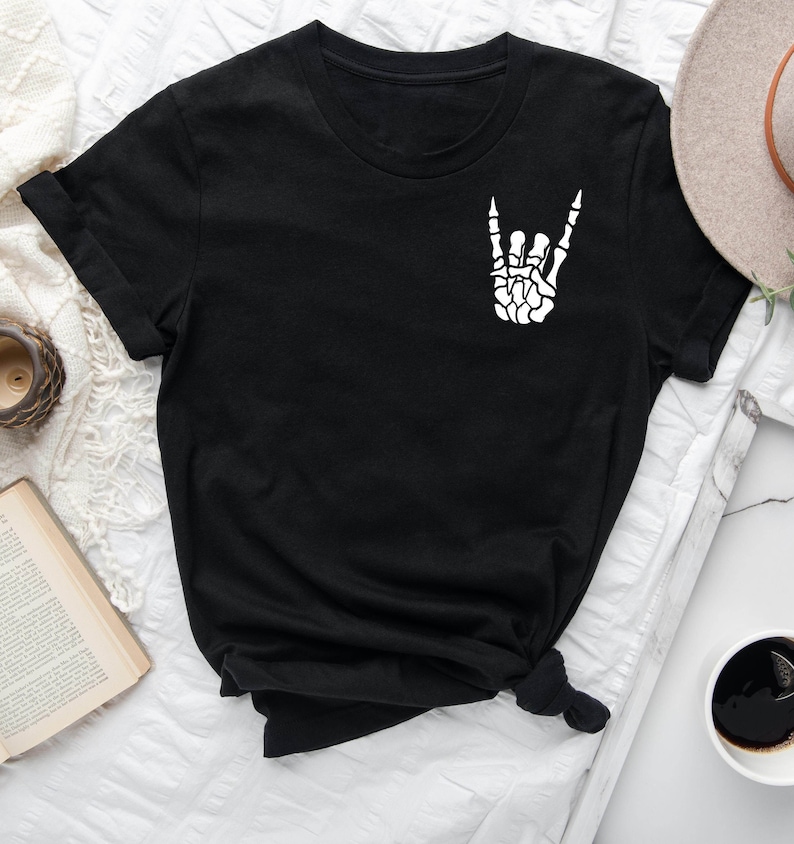 May include: Black t-shirt with a white skeleton hand making the rock and roll hand gesture.