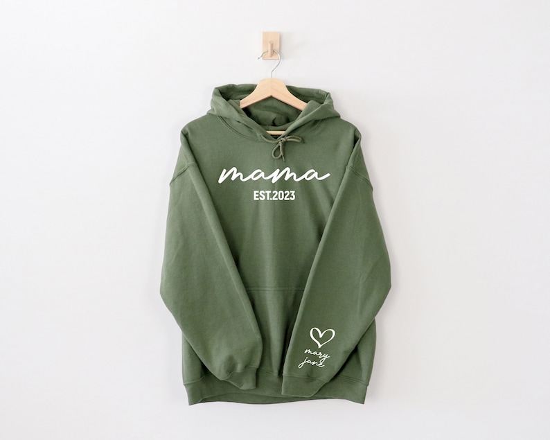 May include: A green hooded sweatshirt with the text "mama est. 2023" on the front and a heart with the text "mary jane" on the sleeve.