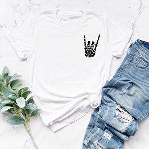May include: White t-shirt with a black skeleton hand making the rock and roll sign.