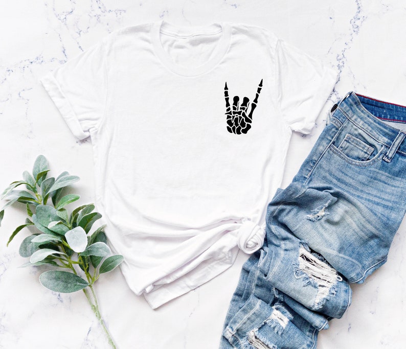 May include: White t-shirt with a black skeleton hand making the rock and roll sign.