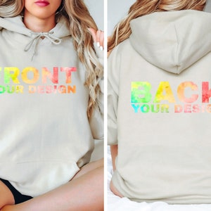 Op de afbeelding: Een licht beige hoodie met een regenboog aquarelontwerp met de tekst "FRONT YOUR DESIGN" aan de voorkant en "BACK YOUR DESIGN" aan de achterkant.