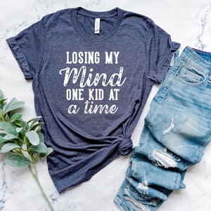 May include: A dark blue t-shirt with the text "Losing My Mind One Kid At A Time" in white lettering.