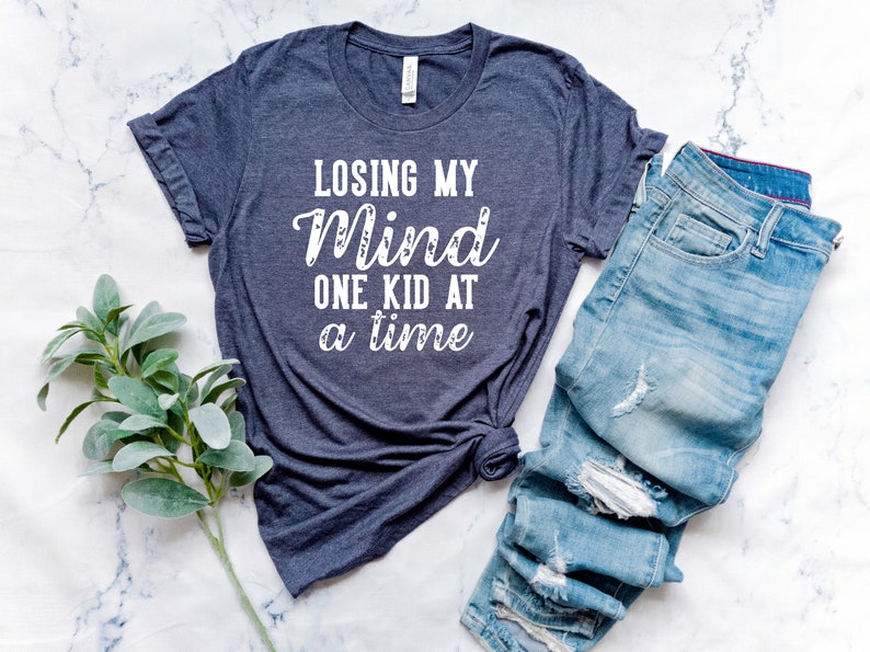 May include: A dark blue t-shirt with the text "Losing My Mind One Kid At A Time" in white lettering.
