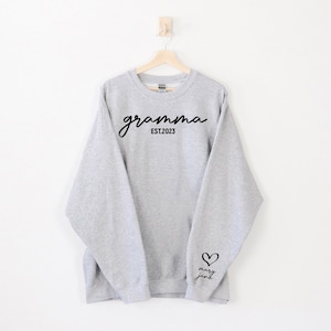 May include: Grey sweatshirt with the text "gramma EST. 2023" on the front and a heart with the text "mary jane" on the sleeve.