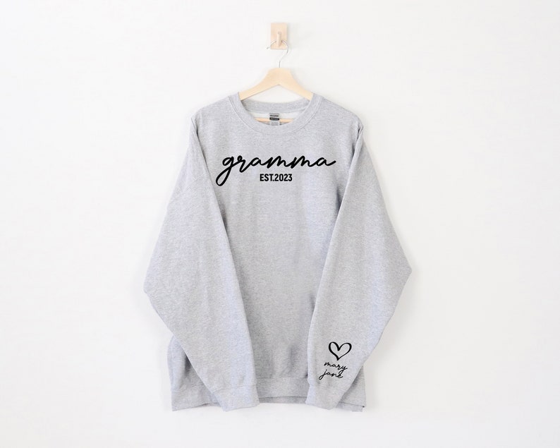 May include: Grey sweatshirt with the text "gramma EST. 2023" on the front and a heart with the text "mary jane" on the sleeve.