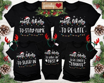 May include: Black Christmas family t-shirts with festive text. Each shirt features a Santa hat and string lights design. Phrases include "Most Likely To Stay Home," "To Be Late," "To Sleep In," "To Wake Up First," and "To Be Santa's Favourite."
