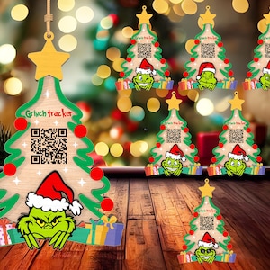 Puede incluir: Conjunto de 8 adornos de árbol de Navidad verde y marrón con una cara de Grinch y un código QR. Los adornos tienen el texto "Grinch Tracker".