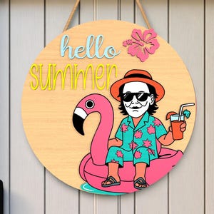 Könnte beinhalten: Runder Holzschild mit den Worten "hello SUMMER" in Blau und Gelb. Eine Cartoonfigur mit Sonnenbrille und Hut schwebt auf einem rosa Flamingo-Schwimmer und hält ein Getränk. Oben befindet sich eine rosa Hibiskusblüte.