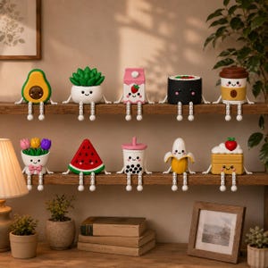 Pode incluir: Uma coleção de dez pequenas figuras coloridas com rostos sorridentes e pernas articuladas pendentes, dispostas em duas prateleiras de madeira. As figuras incluem um abacate, uma suculenta, uma caixa de leite de morango, sushi, café, tulipas, melancia, chá boba, uma banana e uma fatia de bolo.