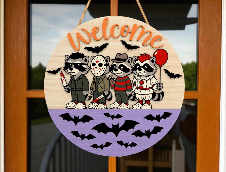May include: A round wooden Halloween welcome sign featuring four cartoon raccoons dressed as horror movie characters. The sign has a light wood top with orange text and black bats. The bottom is purple with bat silhouettes.