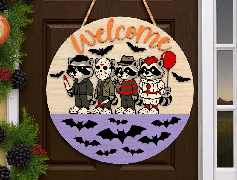 May include: Round wooden Halloween welcome sign featuring cartoon raccoons dressed as horror movie characters. The sign has a light wood grain background with orange "welcome" lettering and a purple lower section with bat silhouettes.