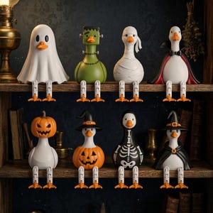 May include: Eight decorative duck figurines dressed in Halloween costumes, including a ghost, Frankenstein's monster, a mummy, a vampire, a pumpkin-headed duck, a witch, a skeleton, and a wizard, all featuring dangling orange webbed feet.