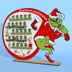 Puede incluir: Un calendario de adviento de madera con el Grinch en un traje rojo de Pap&aacute; Noel, sosteniendo una bolsa de regalos. El calendario tiene 25 casillas numeradas, cada una con una peque&ntilde;a ilustraci&oacute;n de un art&iacute;culo navide&ntilde;o. El texto "Count down to steal Christmas" est&aacute; escrito en un c&iacute;rculo rojo en la parte superior.