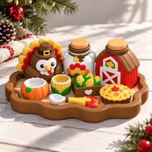 Puede incluir: Un conjunto decorativo que incluye una figura de pavo marrón, un tarro blanco con motivo de pavo, un granero rojo, un cuenco con forma de calabaza, un cuenco con forma de maíz, una caja de maíz, un pastel y una cuchara sobre una bandeja marrón festoneada.