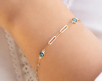 May include: A gold chain bracelet with small blue evil eye charms.