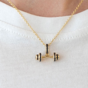 Op de afbeelding: Een gouden ketting met een halter-hanger ingelegd met zwarte diamanten.
