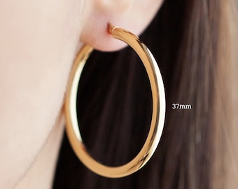 May include: Gold hoop earrings with a diameter of 37 mm.