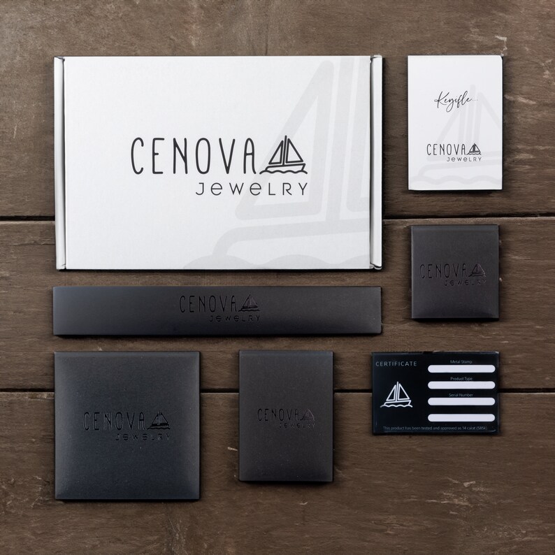 May include: A white box with the text "CENOVA JEWELRY" and a sailboat logo. The box is surrounded by smaller black boxes with the same logo. One box has a certificate inside with the text "CERTIFICATE" and a sailboat logo.