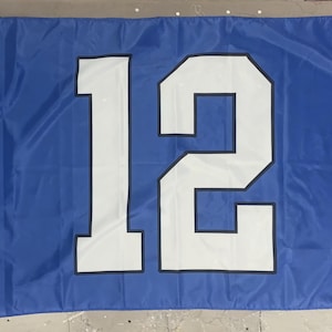 May include: A blue flag with the number 12 in white, outlined in black. The flag is rectangular and appears to be made of a lightweight material. The number is large and centered on the flag.