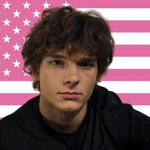 May include: A person with brown curly hair and a black top against a pink and white striped background. The background design resembles the American flag, with pink stripes and white stars.