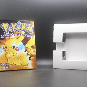 Könnte beinhalten: Eine gelbe Game Boy Color-Spielkassette mit einem Pikachu-Charakter auf der Vorderseite. Das Spiel trägt den Titel "Pokémon Edition Spéciale Pikachu" und ist auf Französisch. Die Kassette befindet sich in einem weißen Plastikgehäuse.