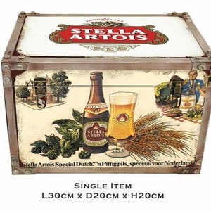 May include: A wooden storage box with a vintage design featuring a Stella Artois beer bottle and glass. The box has a brown wooden frame with metal accents and a cream-colored background. The box is 12 inches long, 8 inches wide, and 8 inches high. "Stella Artois Special Dutch" 'n Pittig pils, speciaal voor Nederland is printed on the box.