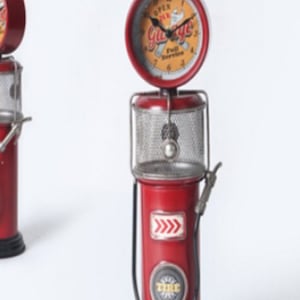 May include: Red metal vintage petrol pump clock with a white face and black hands. The clock face has the words "Open 24 Hr Garage Full Service" and a wrench and screwdriver graphic. The petrol pump has a black hose and a red and white tyre graphic.